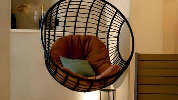 A hanging chair with cushions in a room with a light-colored floor and walls.