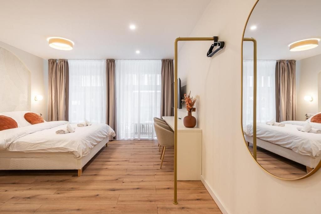 Ett hotellrum med två sängar, ett skrivbord, en stol, en stor spegel och utsikt över omgivningarna.