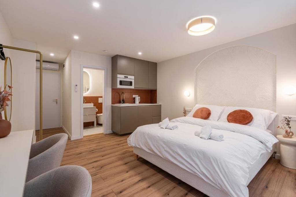 Ett modernt hotellrum med en stor säng, ett skrivbord, ett litet kök och ett badrum.