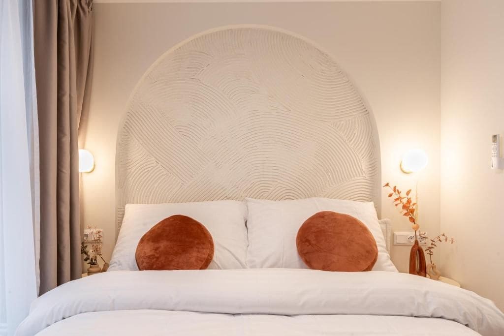 A bed with a large, textured headboard, two pillows, and bedside lamps.