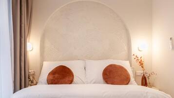 A bed with a large, textured headboard, two pillows, and bedside lamps.