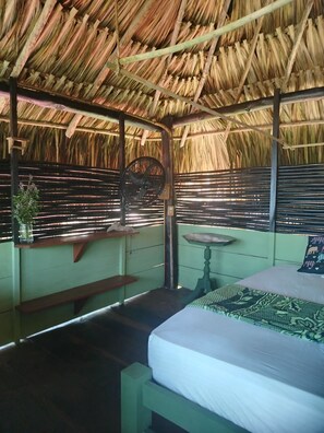Ein Zimmer mit einem Bett, einem Tisch, einer Bank und einem Ventilator.