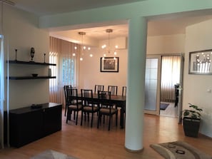 Un área de comedor con una mesa, sillas, un armario negro y una planta en maceta.