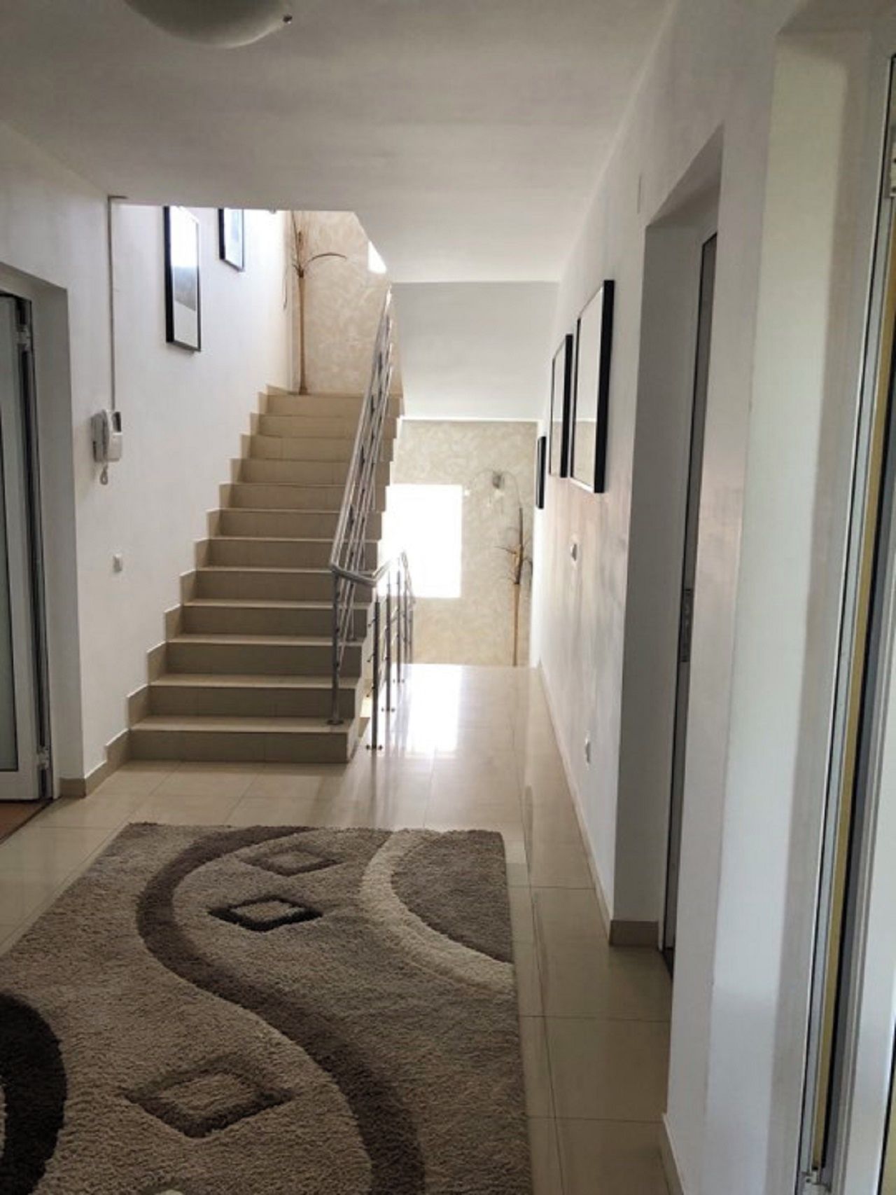 Un couloir avec un tapis, un escalier et une porte.