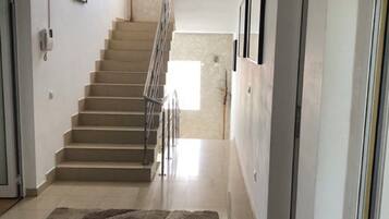 Un couloir avec un tapis, un escalier et une porte.