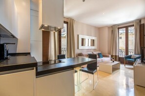 A modern kitchen with a central island, a dining area with a sofa and chairs, and a living room with a large window and curtains. - New Listing (Granada)