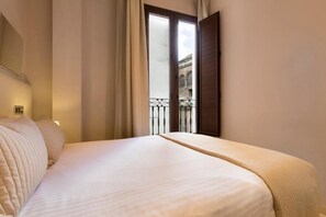A hotel room with a large bed, a window with curtains, and a view of a building outside. - New Listing (Granada)