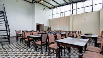 Un comedor amplio con varias mesas y sillas, suelo estampado y techo alto con luz natural.