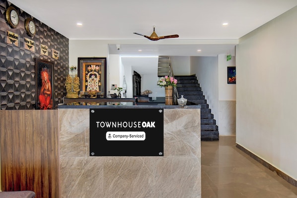 A reception desk with a marble top, a framed religious statue, and a wall clock.