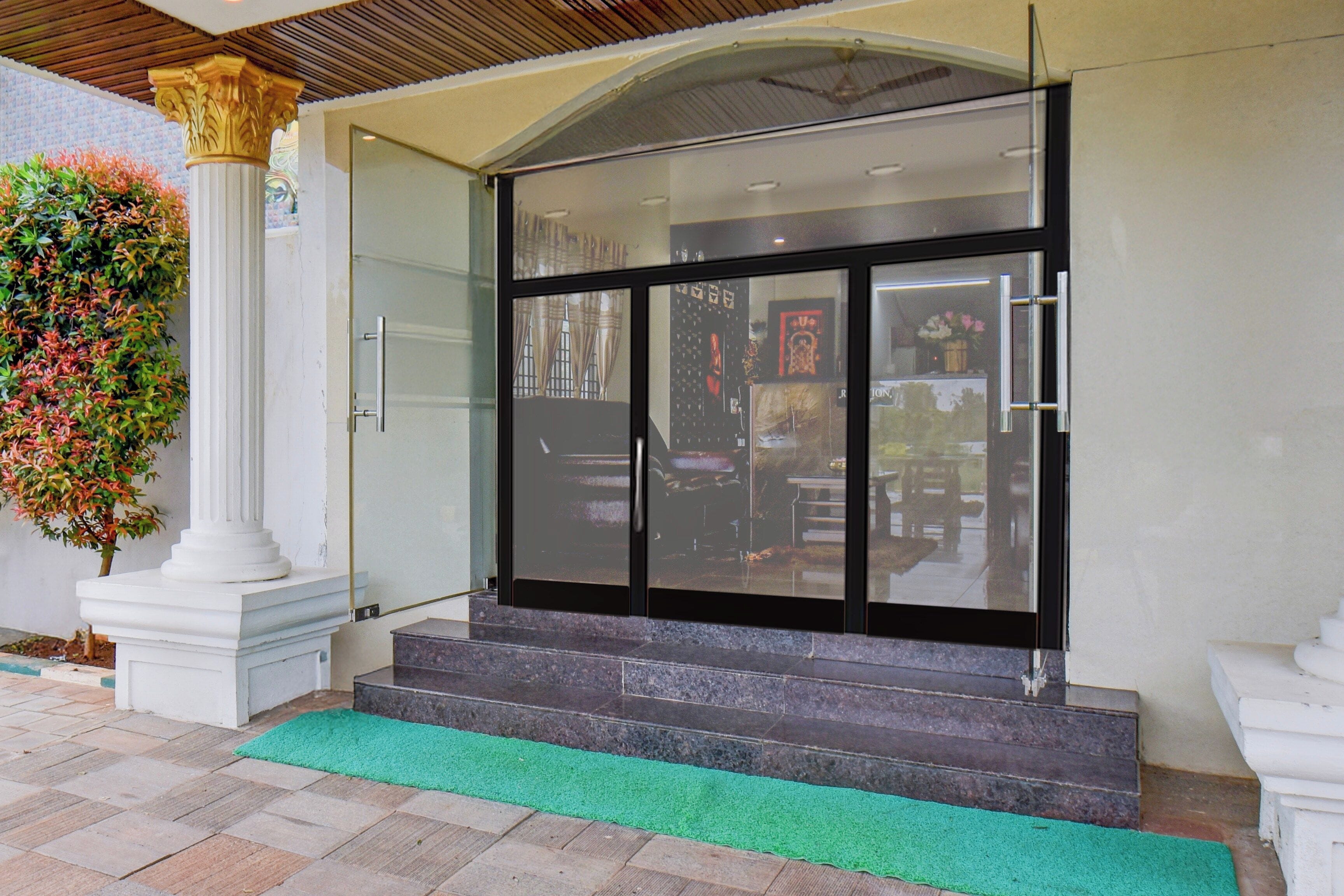 A building entrance with a glass door, steps, and a green mat.