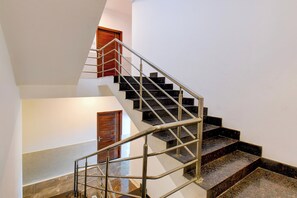 Un interior de varios niveles con una escalera de barandillas metálicas y escalones oscuros.