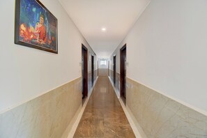 Corredor com piso de mármore, um quadro na parede esquerda e portas em ambos os lados.