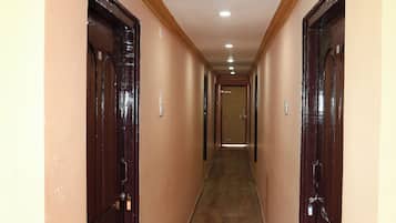 Un pasillo largo y estrecho con suelo de madera y puertas de madera oscura a ambos lados.