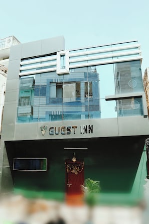 A modern building with a sign reading 'GUEST INN' at the entrance. - Spot On V GUST IN (Tenali)