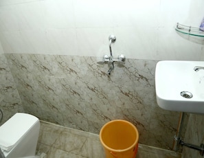 A bathroom with a white sink, a shower with a chrome faucet, and a marble-patterned wall. - Spot On V GUST IN (Tenali)