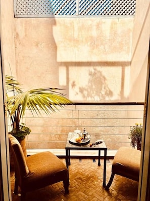 A small patio area with two chairs, a table, and a potted plant. - Maison D'Hôtes DAR LES SIRENES (Essaouira)