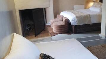 Un dormitorio con una cama, chimenea y mesita de noche.