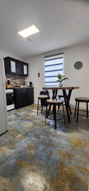 A compact kitchen with modern appliances, a dining area with a table and chairs, and a large window with blinds. - Nice Place to Relax Leve I (Fajardo)