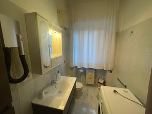 Casa de banho com lavatório, espelho, sanita e zona de duche.