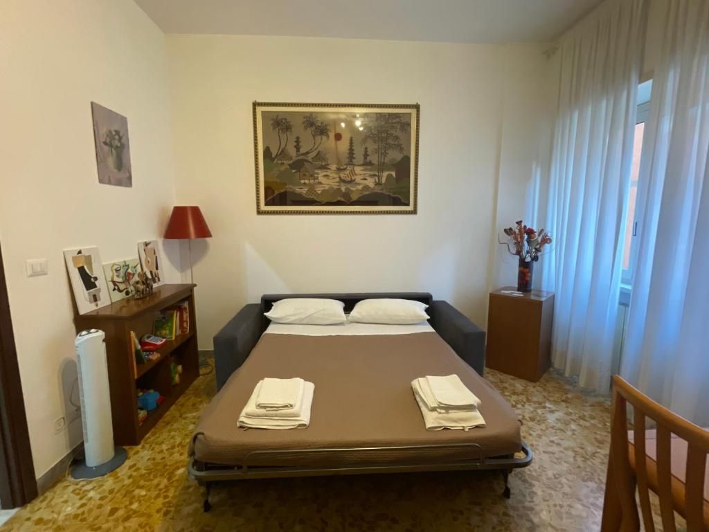 Une chambre à coucher avec un lit, une table de chevet, une lampe, une bibliothèque et un tableau accroché au mur.