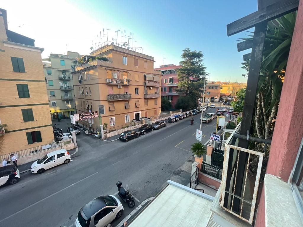 Vista da rua com edifícios, carros estacionados e céu limpo.