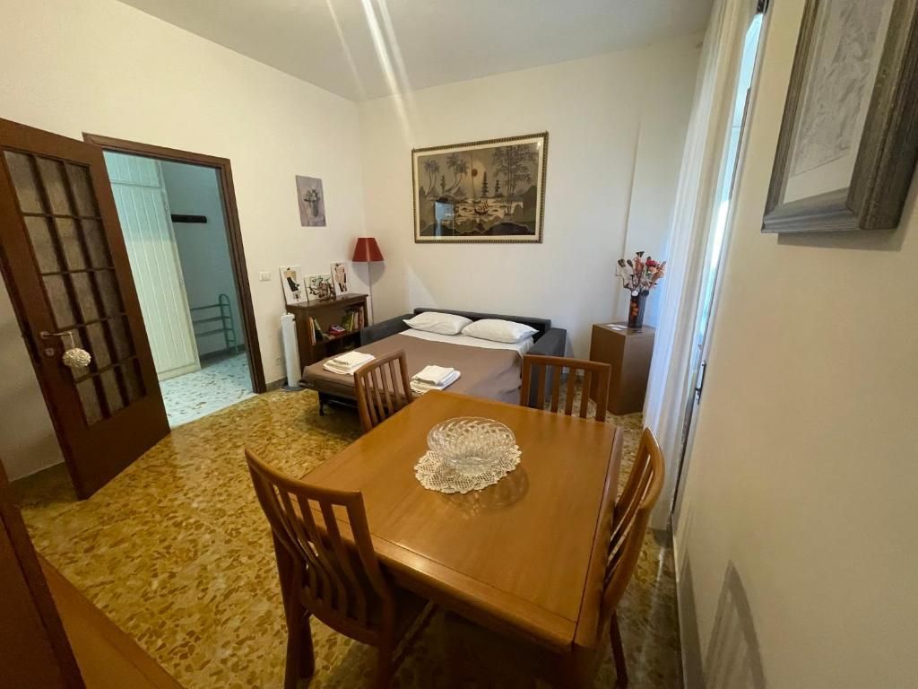 Quarto com cama, mesa de jantar com cadeiras, um quadro na parede e porta que dá para outro cômodo.