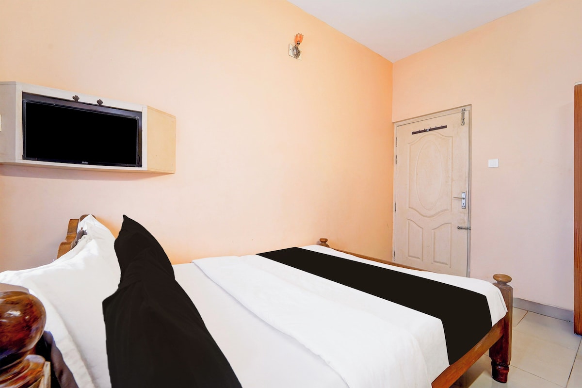 A hotel room with a bed, a television mounted on the wall, and a door.