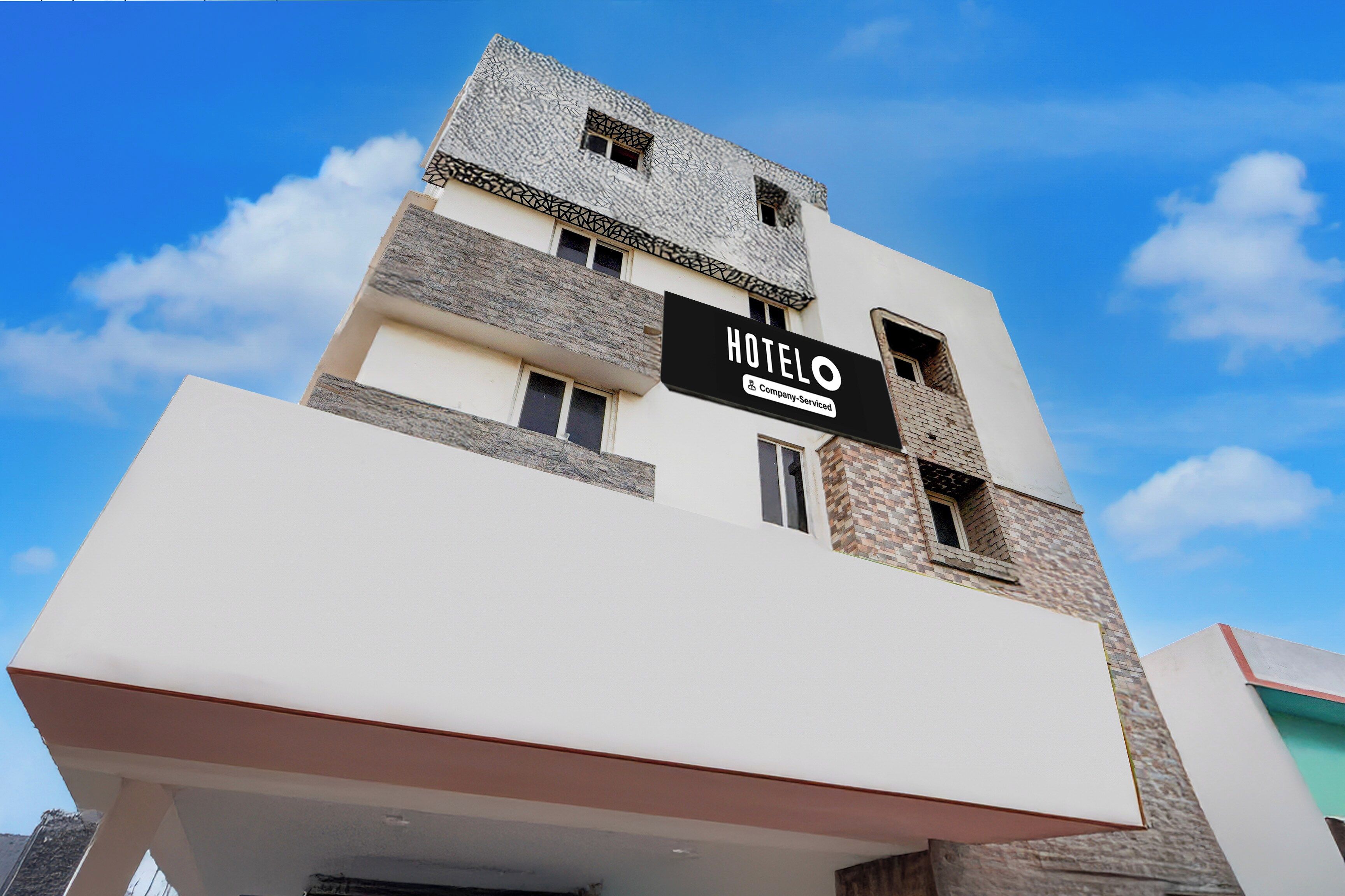 Um edifício de hotel moderno com uma placa indicando 'HOTEL' e 'Company-Serviced'.