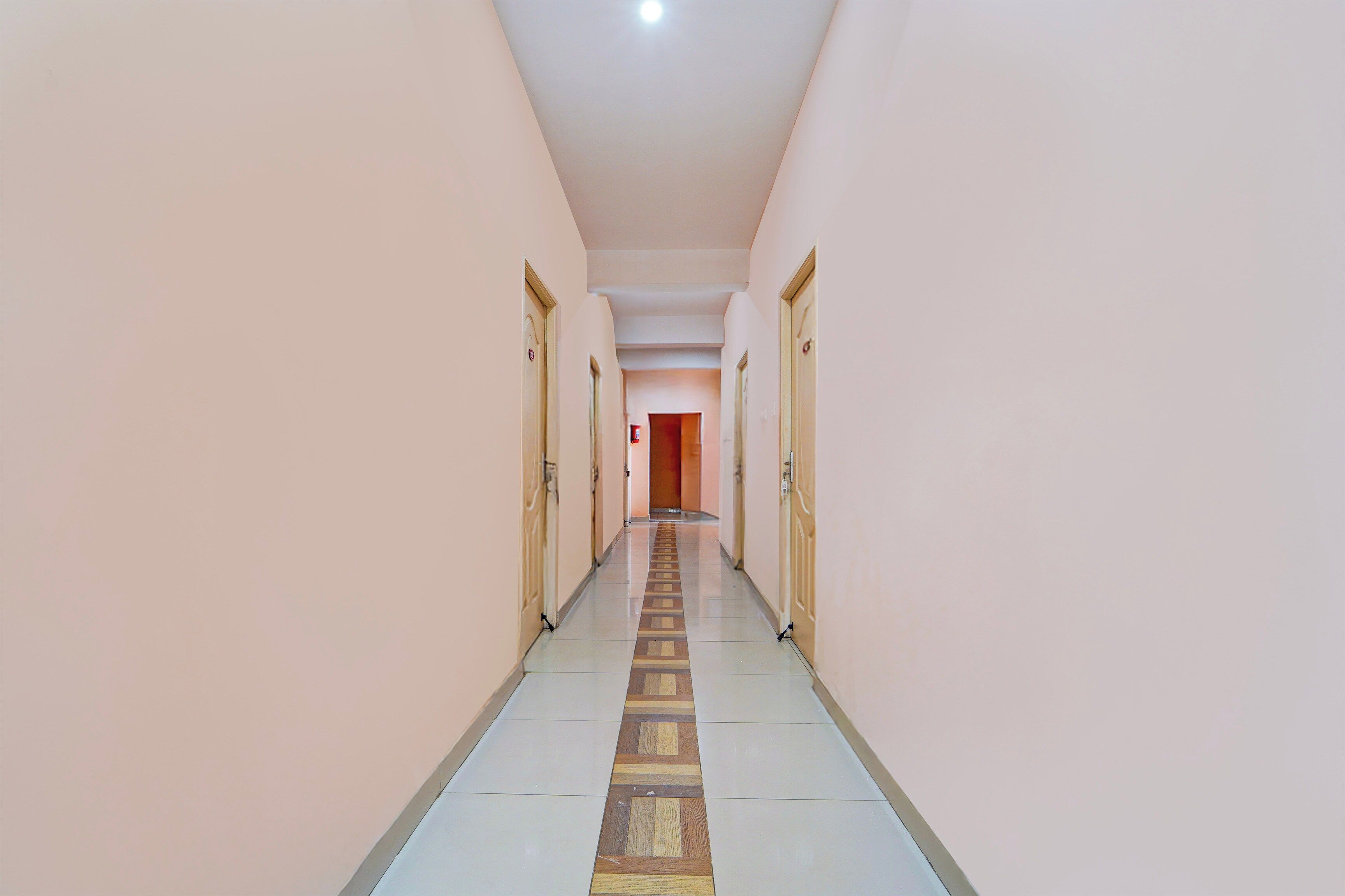 Un couloir bordé de portes des deux côtés, qui mène à une pièce au bout.