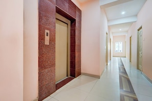 Un pasillo con pared de mármol, una puerta con panel de control y un suelo estampado.