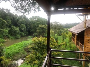 A wooden structure with a balcony overlooking a river and dense greenery. - Streamedge Resort (Sakleshpur)