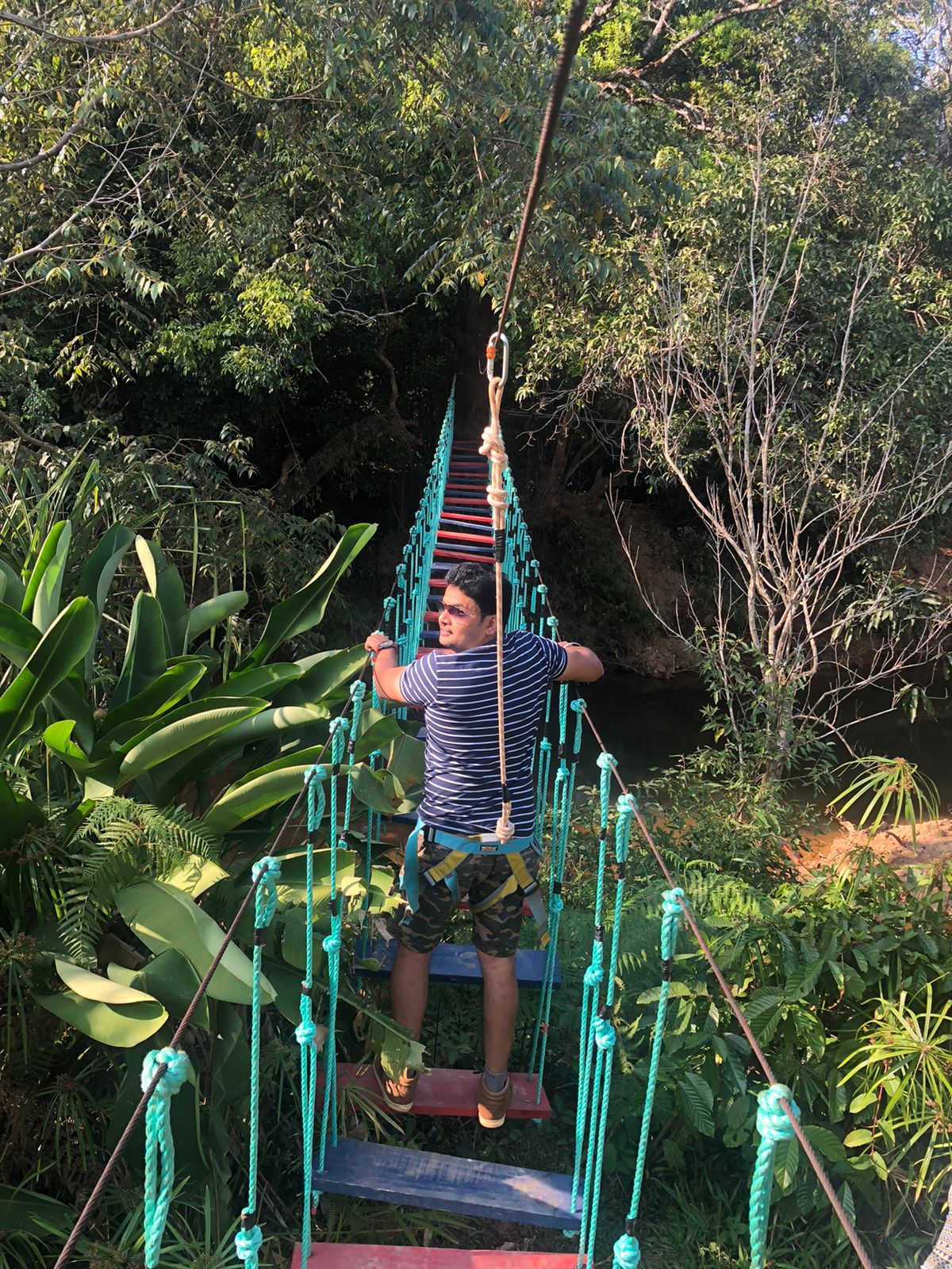 A person on a rope bridge in a natural setting.