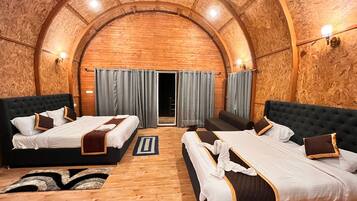 A room with two beds, a wooden ceiling, and a view through a door.