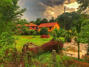 A house with a red roof, surrounded by lush greenery and a garden. - Streamedge Resort (Sakleshpur)