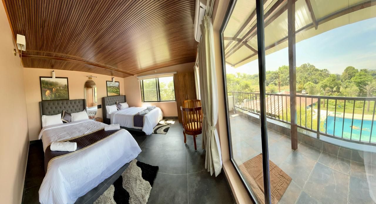 A hotel room with two beds, a balcony with a view of a swimming pool, and a wooden ceiling.