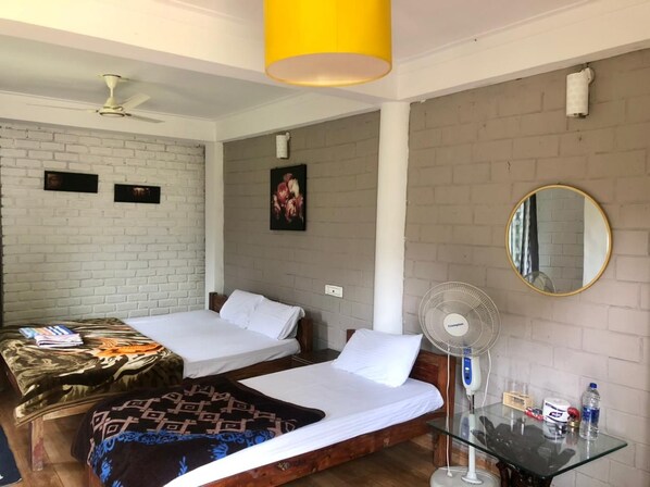 A room with two single beds, a ceiling fan, a table with a mirror, and a wall-mounted fan. - Streamedge Resort (Sakleshpur)