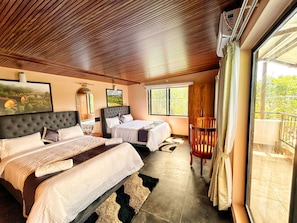A hotel room with two beds, a wooden ceiling, large windows, and a view of greenery. - Streamedge Resort (sakleshpur)