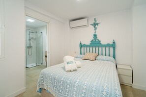 A bedroom with a bed, a wall-mounted air conditioner, and a shower area. - Cubo's Casa La Roca / urban / air conditioning / terrace / free Wi-Fi (Alhaurín el Grande)