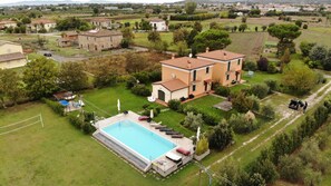 Una propiedad residencial con piscina, cancha de tenis y un jardín amplio.