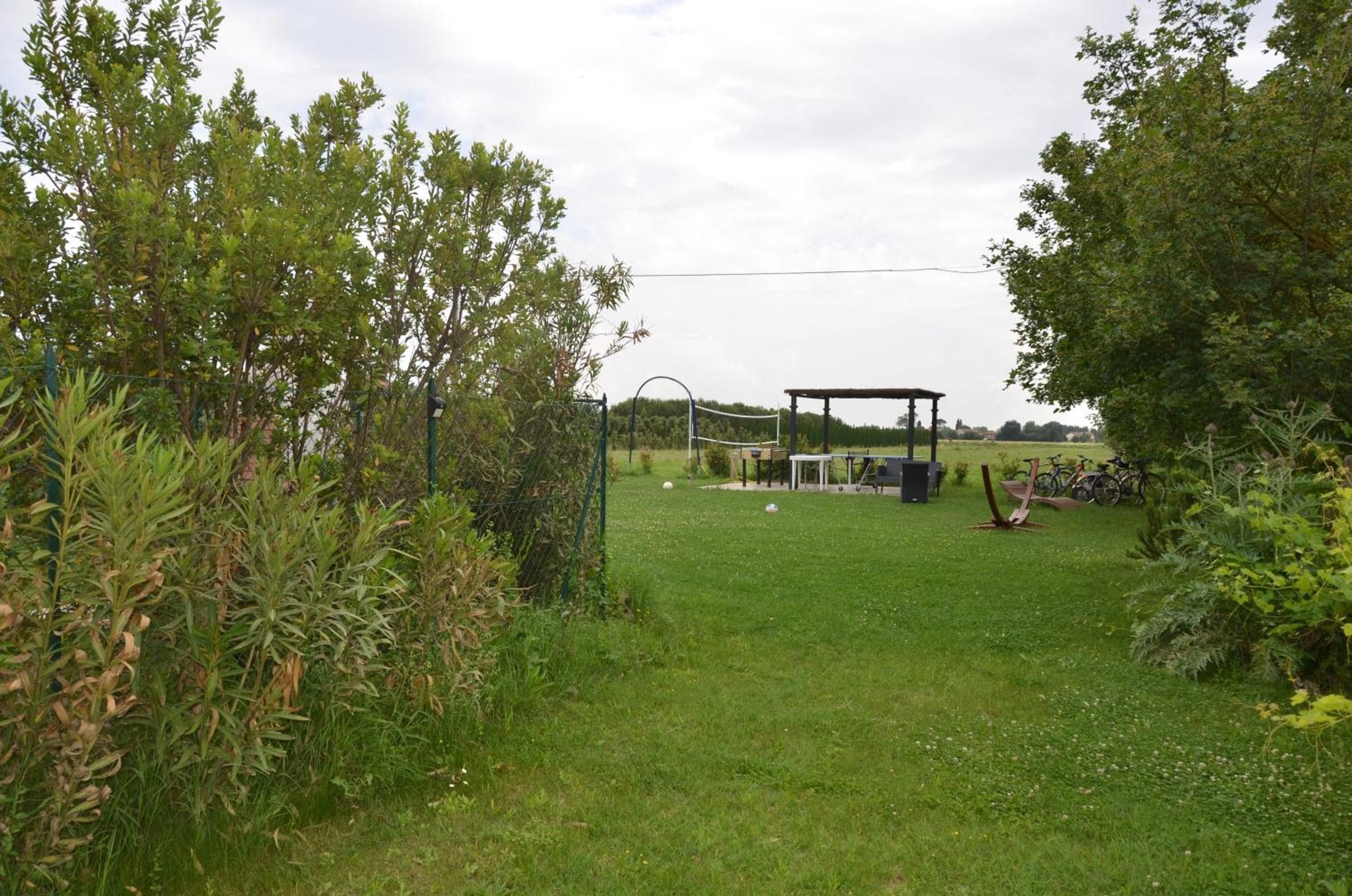A grassy outdoor area with a gazebo, a volleyball net, and bicycles.