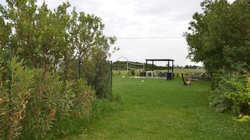 A grassy outdoor area with a gazebo, a volleyball net, and bicycles.