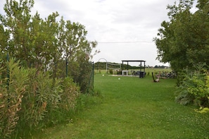 Eine begrünte Außenanlage mit einem Pavillon, einem Volleyballnetz und Fahrrädern.