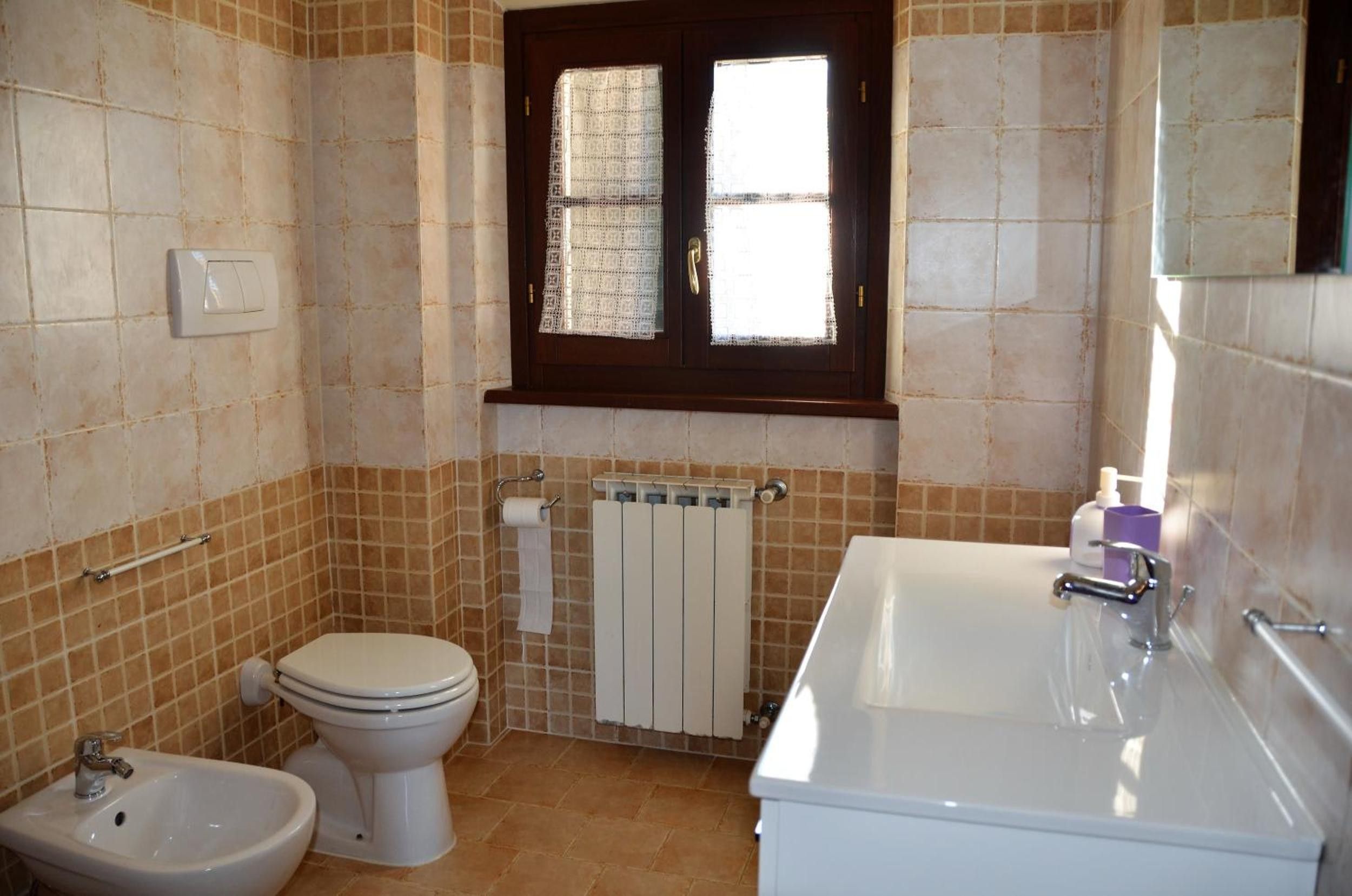 Une salle de bain équipée de toilettes, d’un bidet et d’une baignoire.