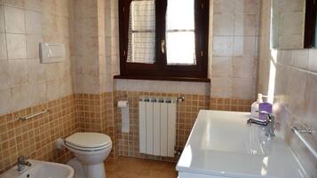 Une salle de bain équipée de toilettes, d’un bidet et d’une baignoire.