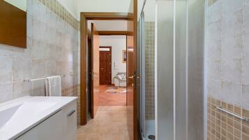 Une salle de bain avec une douche, un lavabo et un porte-serviettes.