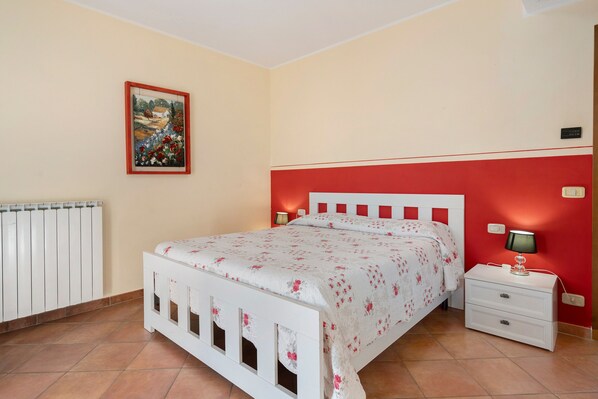 A bedroom with a bed, nightstand, and a painting on the wall.
