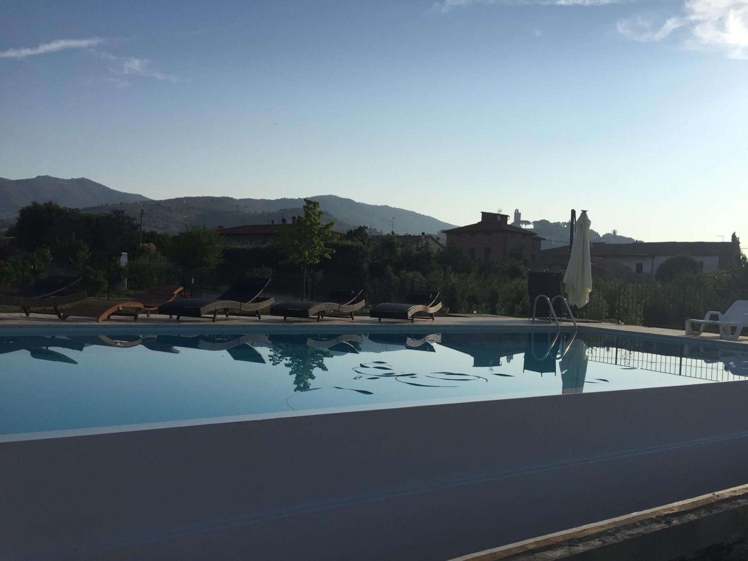 Ein Swimmingpool mit Liegestühlen und Bergblick im Hintergrund.