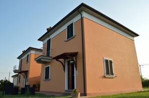 Ein zweigeschossiges Wohngebäude mit Balkon und kleiner Veranda.