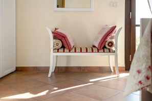 A bench with a patterned cushion and a wall-mounted mirror.