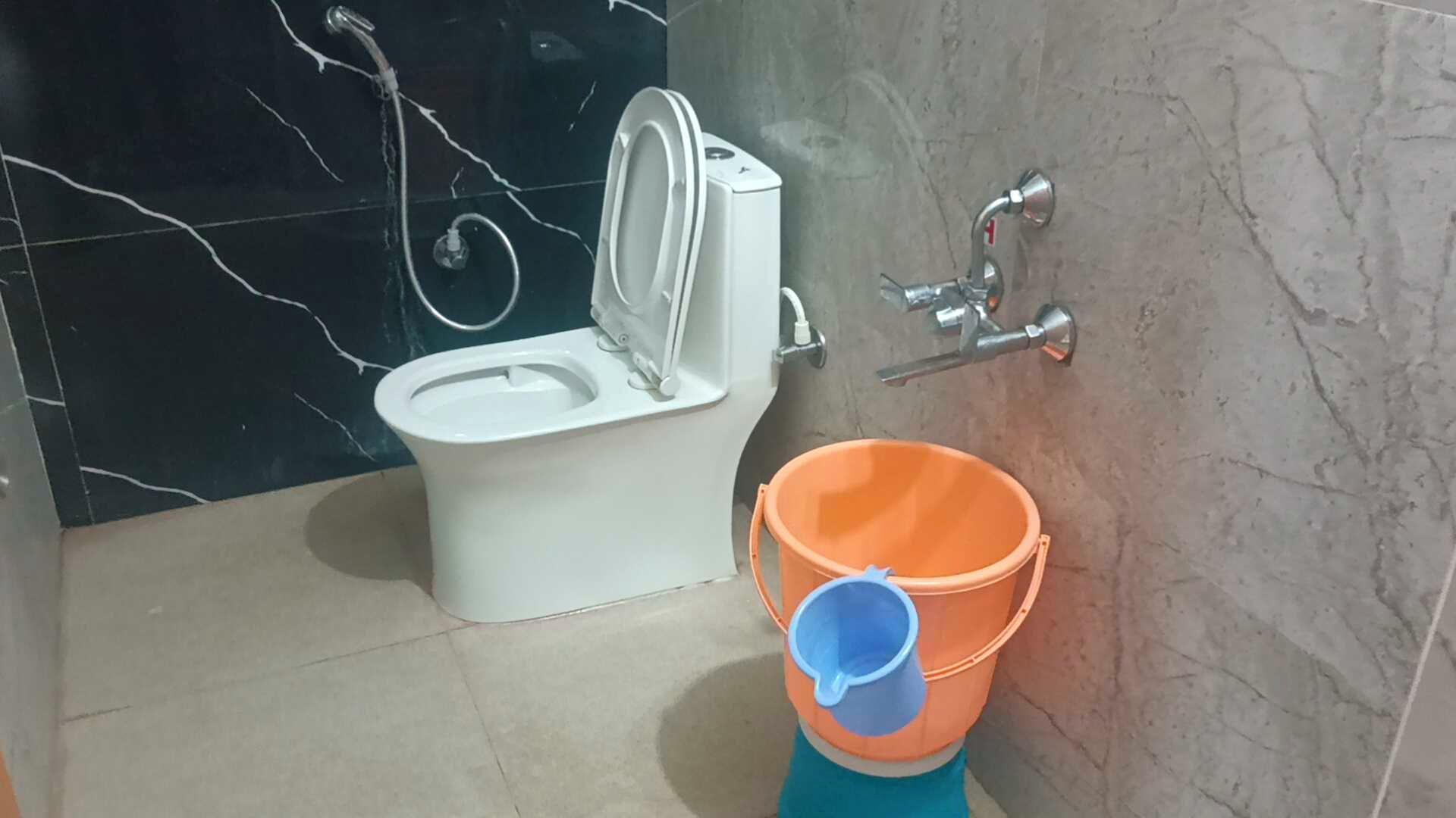 Un baño con inodoro, bidé y un cubo.